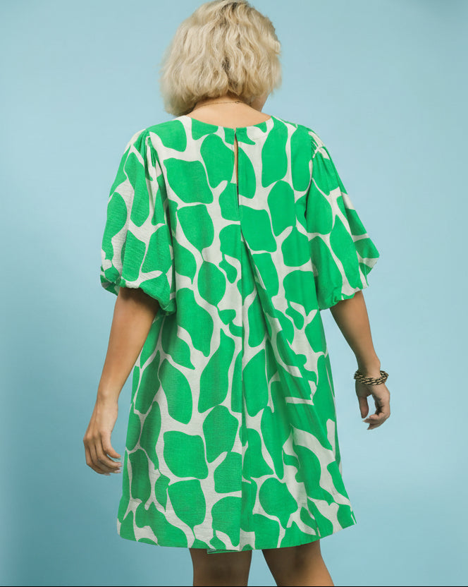 Woman wearing a green and white patterned dress against a light blue background