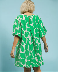 Woman wearing a green and white patterned dress against a light blue background