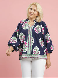 Woman wearing a navy blouse with floral patterns on a pink background