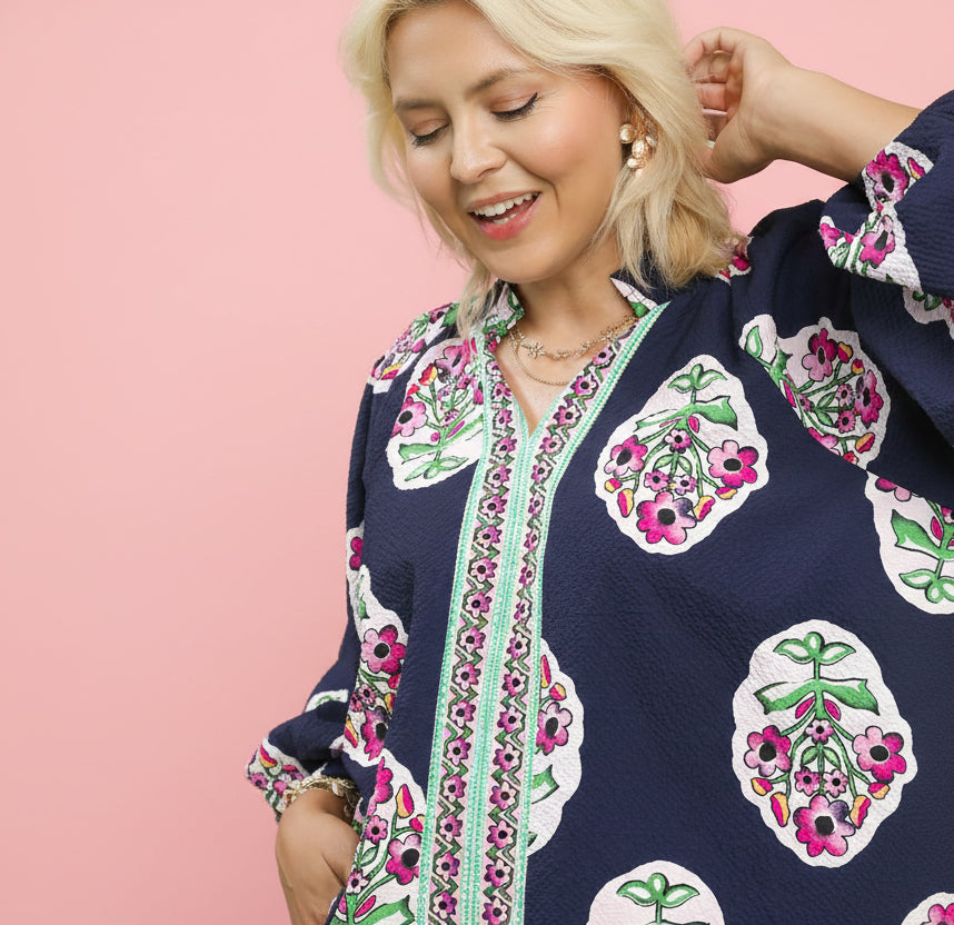 Woman wearing a navy blue top with floral patterns on a light pink background