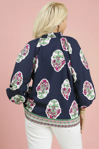 Woman wearing a navy blue blouse with floral patterns on a light pink background
