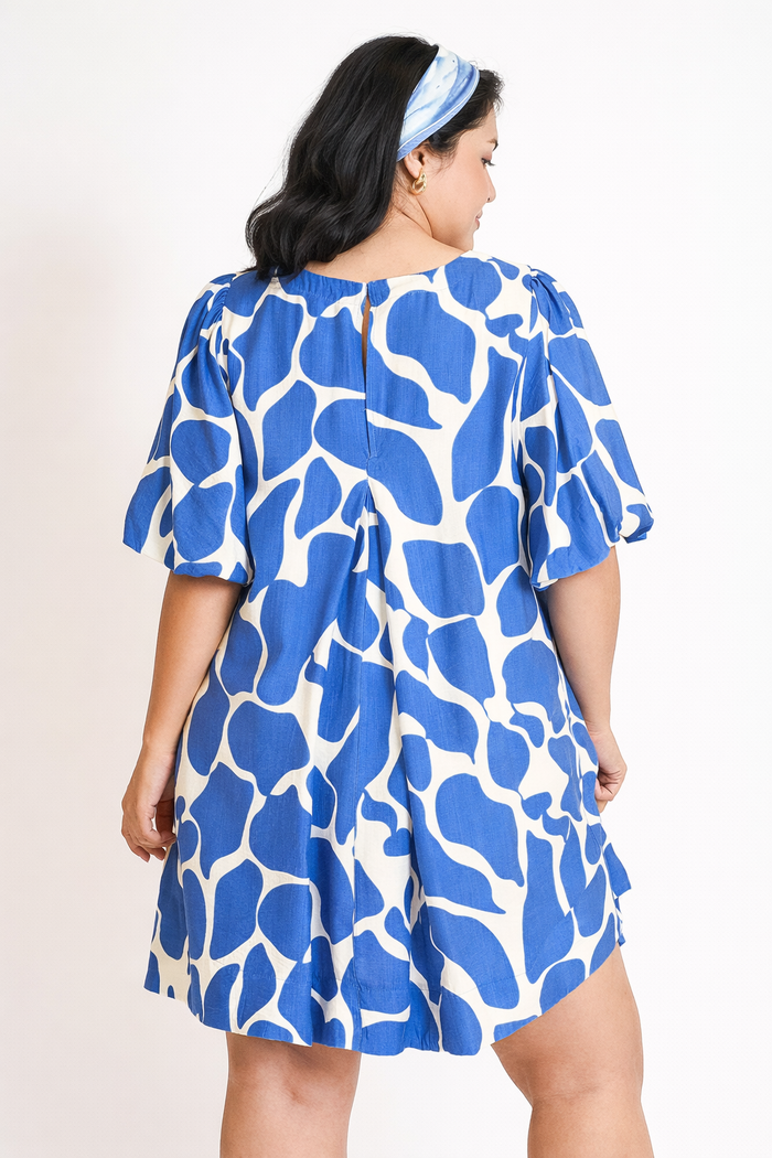 Woman wearing a blue and white patterned dress on a plain background