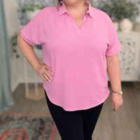 Person wearing a pink polo shirt in an indoor setting