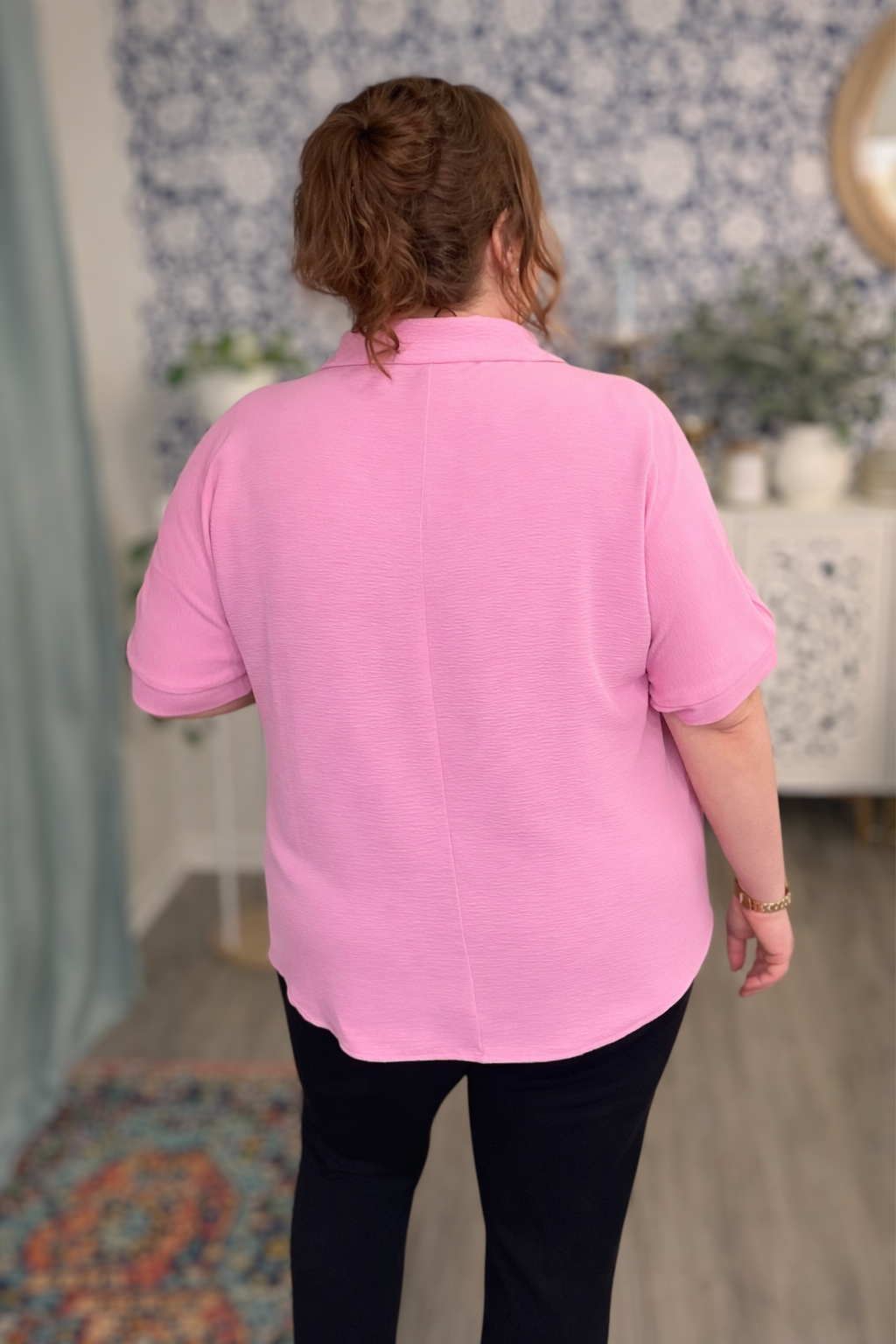 Person wearing a pink shirt in a room with decorative elements