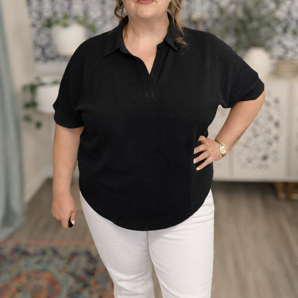 Person wearing a black short-sleeve shirt and white pants in an indoor setting