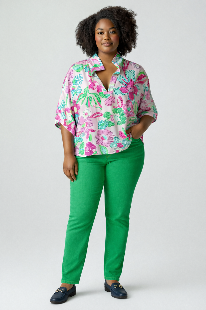 Woman wearing a colorful floral blouse and green pants on a white background