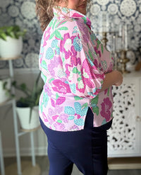Person wearing a pink floral blouse in a room with decorative elements.