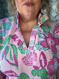 Person wearing a colorful patterned shirt with pink, green, and purple design.