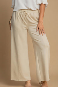 Beige wide-leg pants worn by a person on a brown background