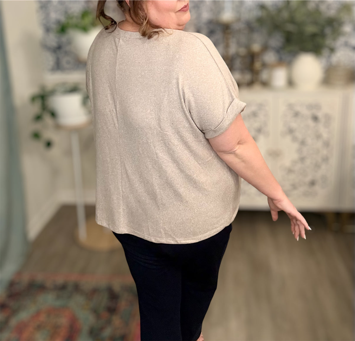 Person wearing a beige shirt and dark pants in an indoor setting