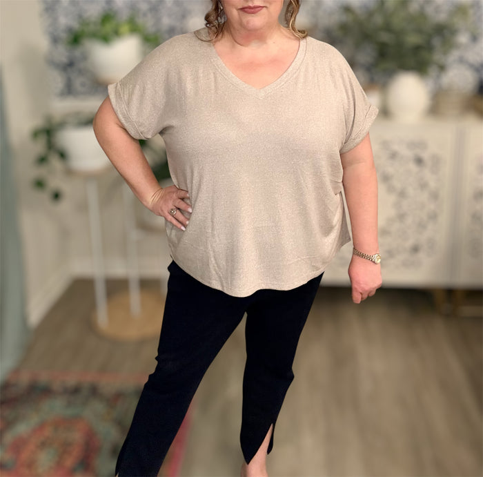 Woman wearing a beige top and black pants in an indoor setting
