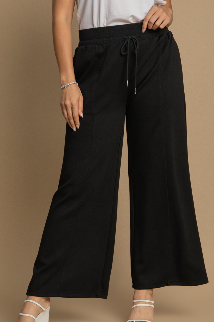 Black wide-leg pants worn by a person on a beige background